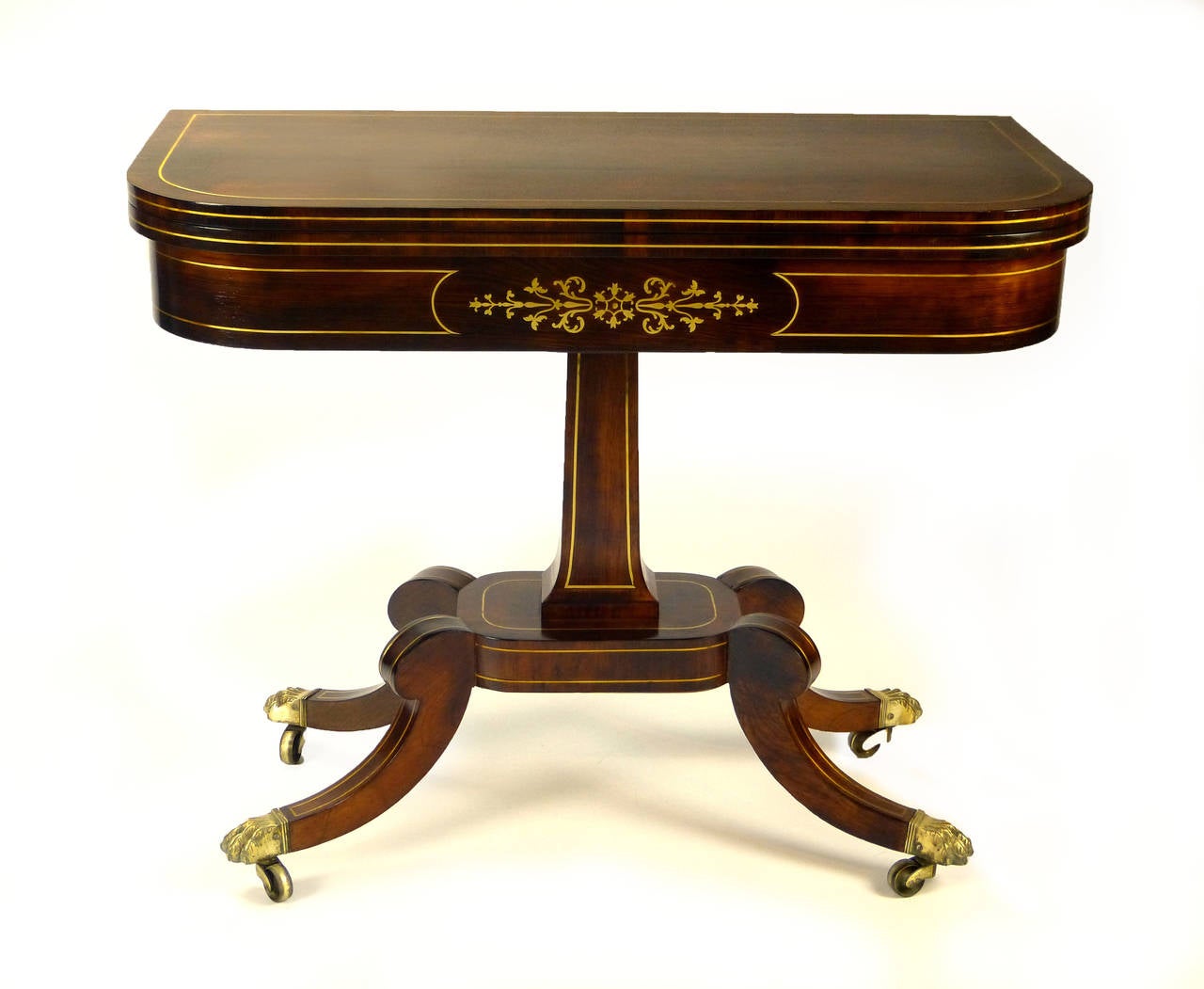 Elegant Regency games / card table created entirely of Indian rosewood and profusely brass inlaid throughout. The two tops turn 90º and unfold book style revealing a newly upholstered Ralph Lauren distressed leather playing surface. Below the
