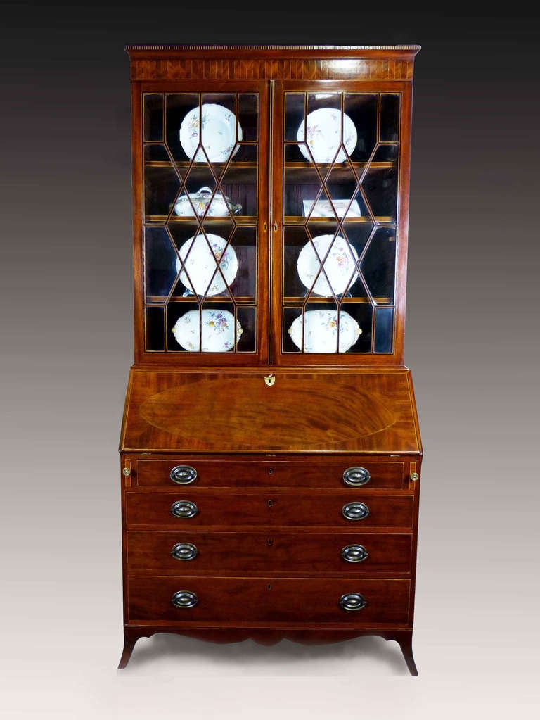 Fine mahogany Georgian bureau bookcase in the Hepplewhite style with line inlay of ebony and satinwood throughout. The two door bookcase is ebony inlaid with geometric astragal design and original glazing. Above, a finely inlaid herringbone cornice