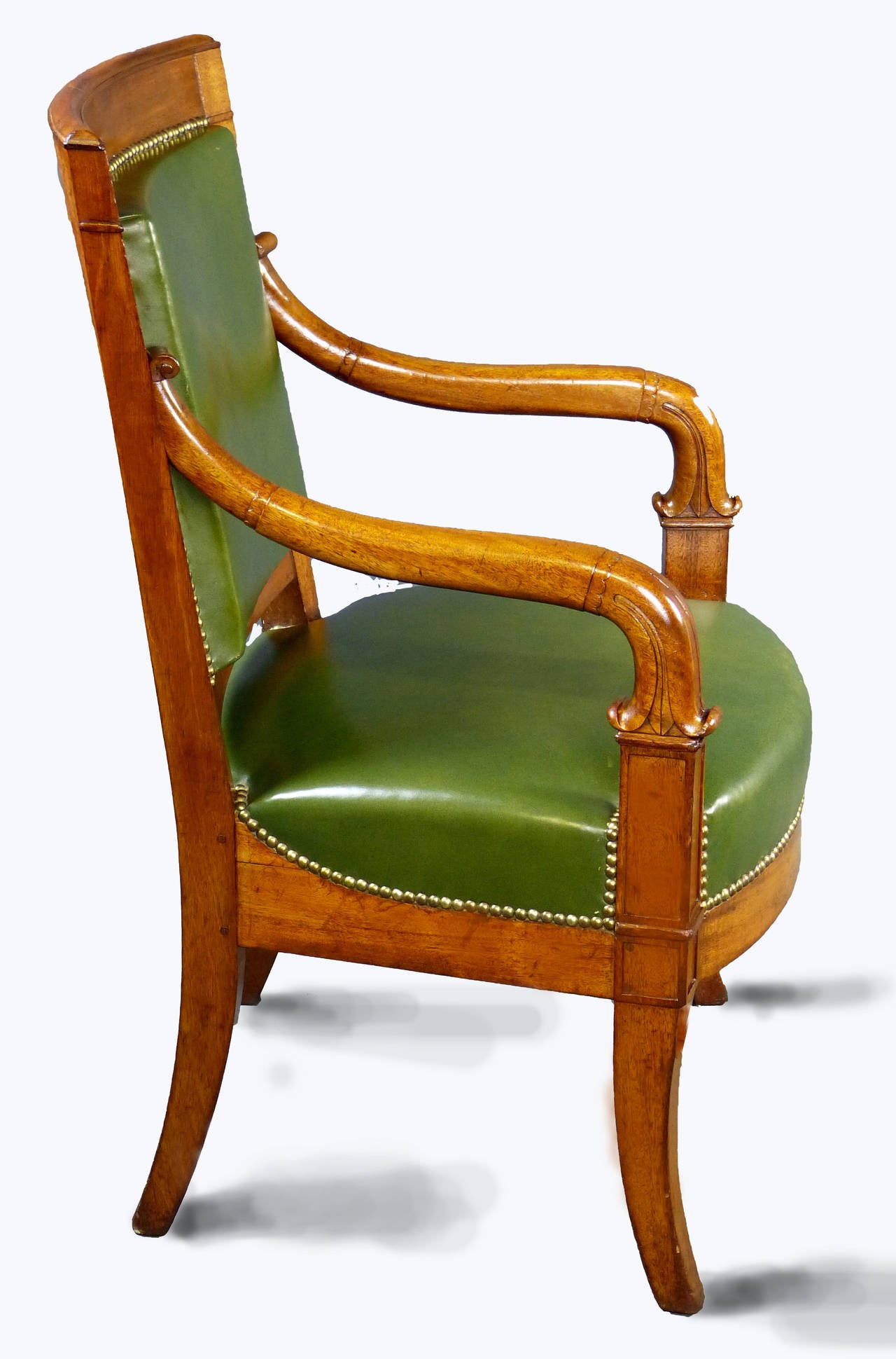 French blond mahogany armchair of the Louis Philippe period, middle of 19th century, with its patina and original condition beautifully preserved. The curved arms terminate in stylised dolphin head carvings. Front and rear sabre shaped legs.