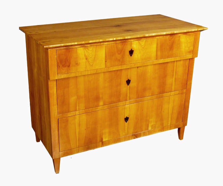 Outstanding Commode of the Biedermeier period of south-central German origin, created from figured cherry veneers over northern pine (aka pinotea). Three drawers with black buffalo horn escutcheons/keyholes of shield form over four small tapering