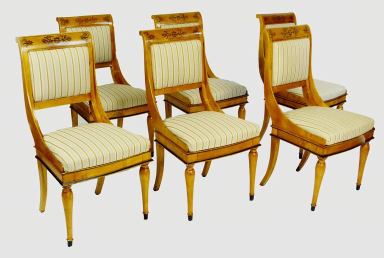 Exquisite and rare set of six dining chairs of the Biedermeier period and of Austrian origin, created with maple and birchwood. There are fine hand-painted designs on the upper part of the back splats which curve in S-form to attach onto a