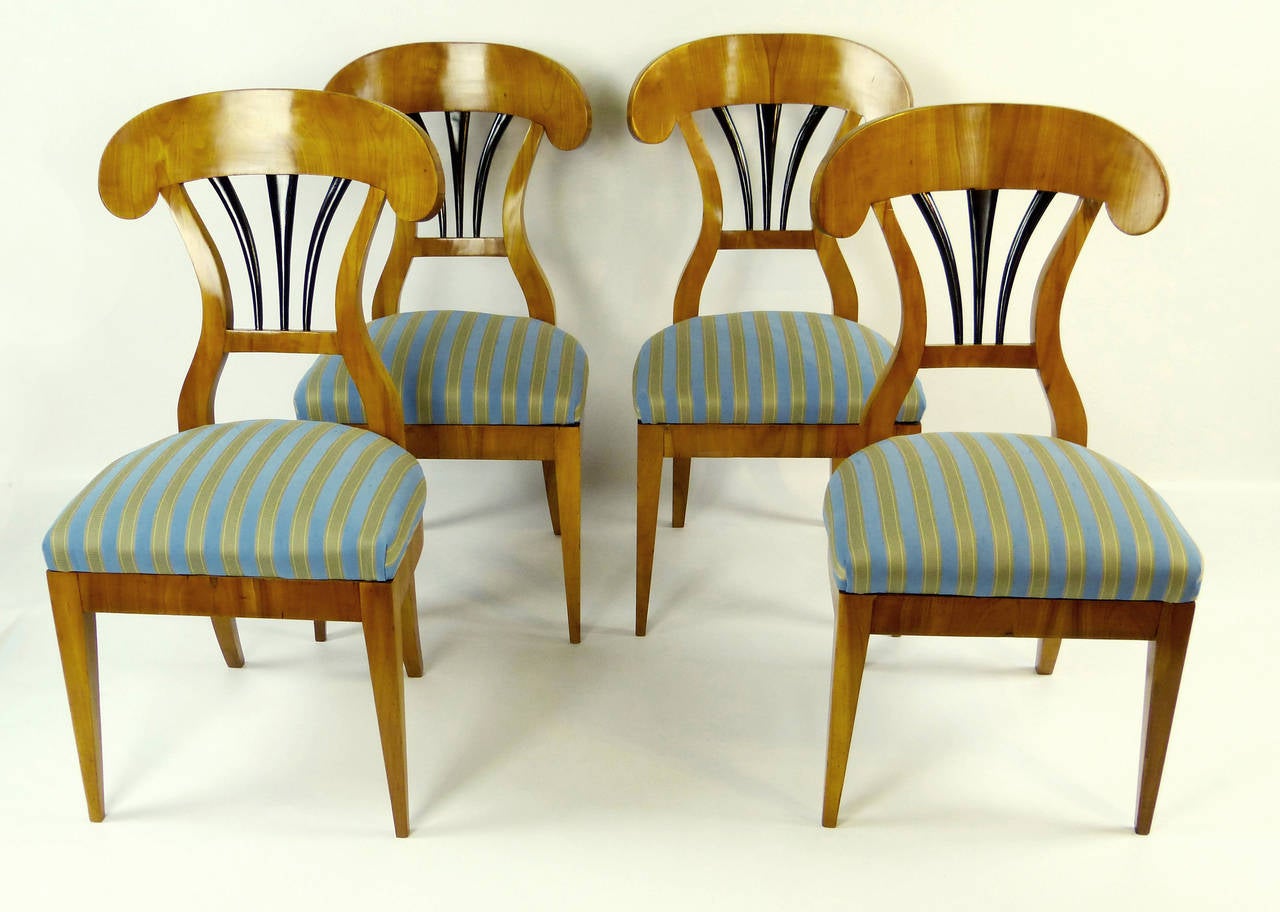 Exquisite pair of 2 light colored cherry chairs of the first Biedermeier period and of southcentral German origin, dating to the first quarter of the 19th century. The arched back-splats characteristic of this style with ebonized fan design below