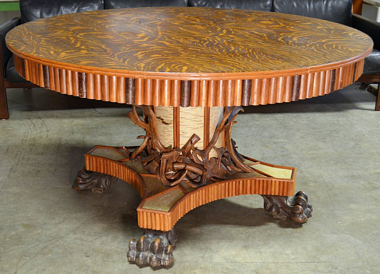 1890's tiger oak top table with center column pedestal and  carved paw feet detailed in the Adirondack taste. The apron is trimmed in split twig. Column and base are adorned with birch bark twig and antlers. Table is late 19th century and the