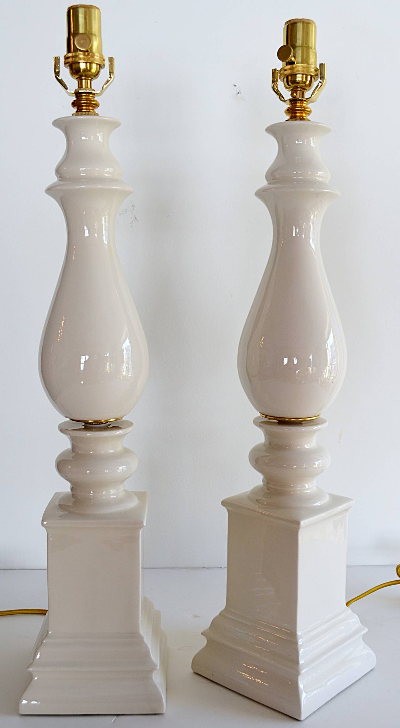 A wonderful tall pair of creamy white baluster form blanc de chine table lamps with brass accents. New wiring and sockets