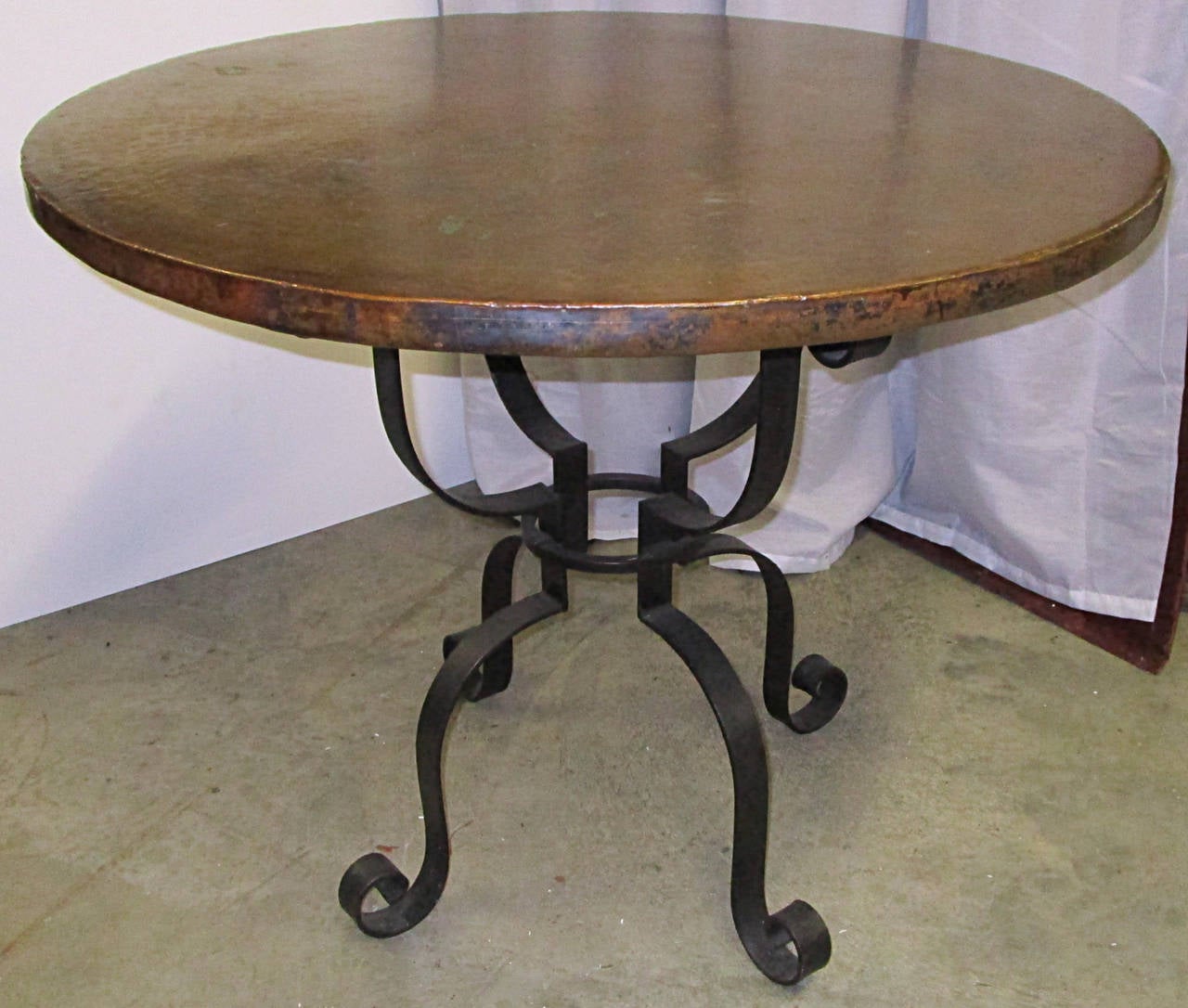 Simple and elegant occasional copper top table. Hour glass form, four point black steel base with curl details. Warm coloration to copper.