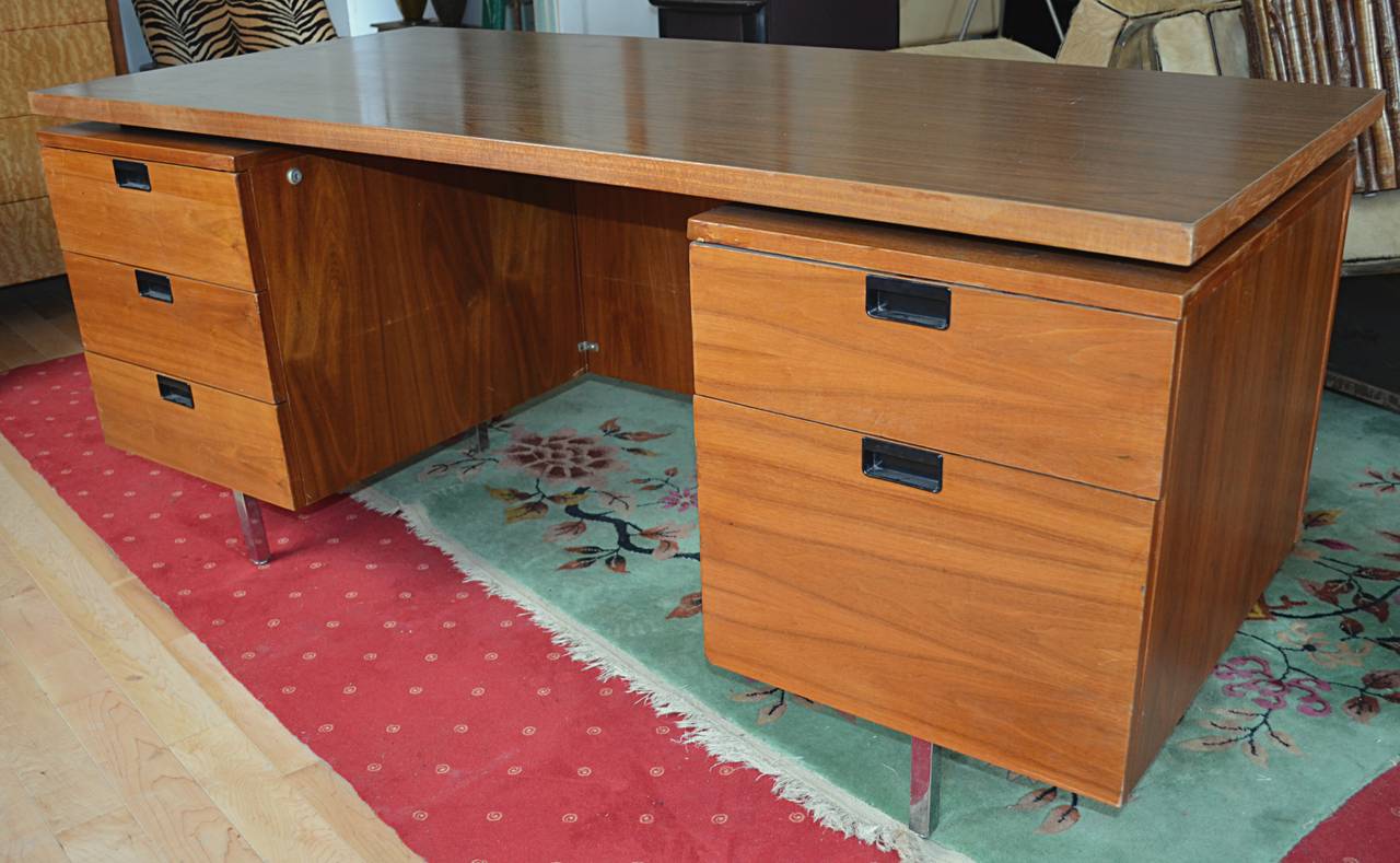 Five drawer desk executed in walnut with floating laminate top on chrome feet.