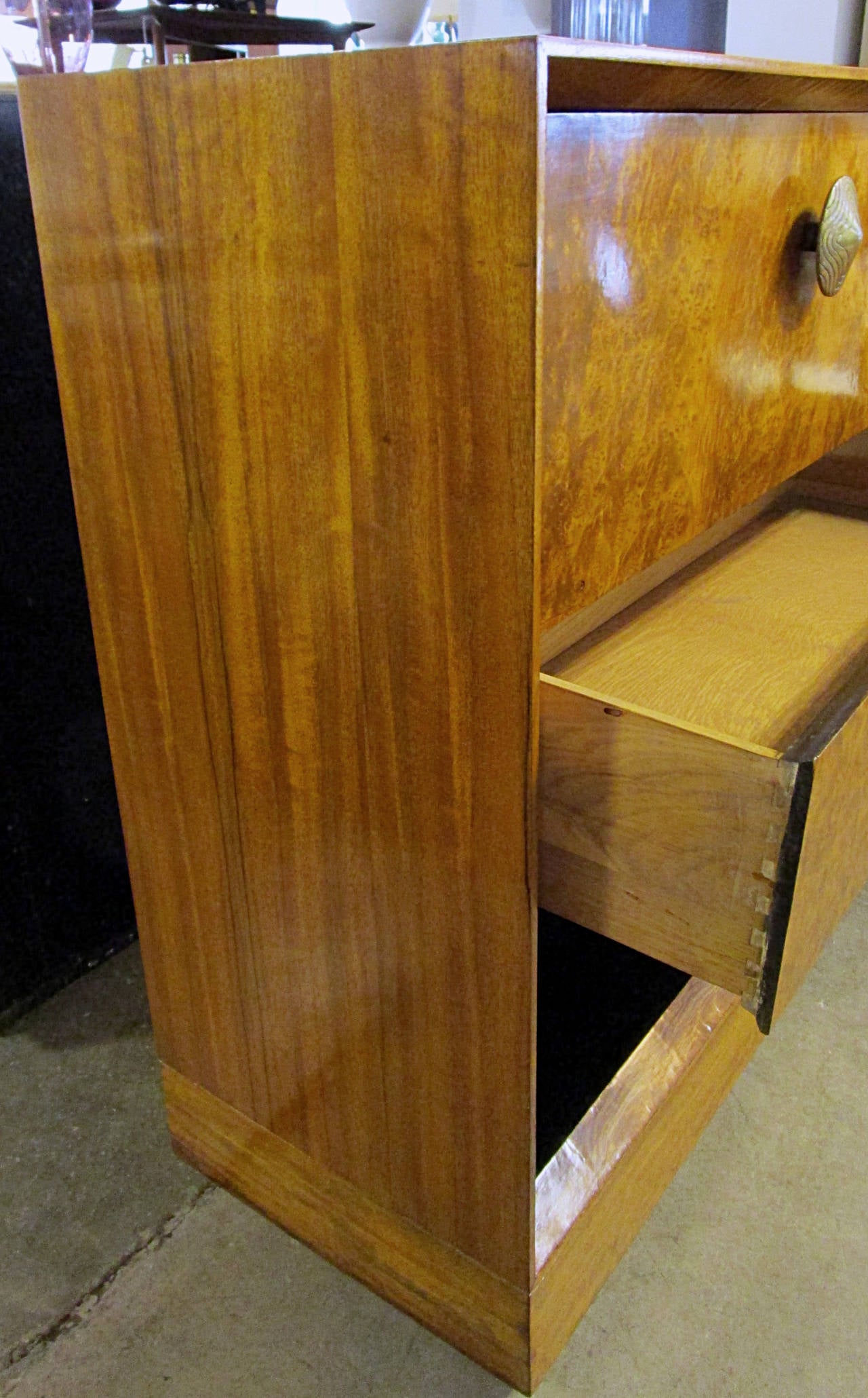 An exquisite deco cabinet designed by Gilbert Rohde in 1940 for Herman Miller. This piece is comprised of Paldao wood for the top sides and base with a beautiful Acacia burl for the drawer and drop front as well as interior beveled edge. Interior