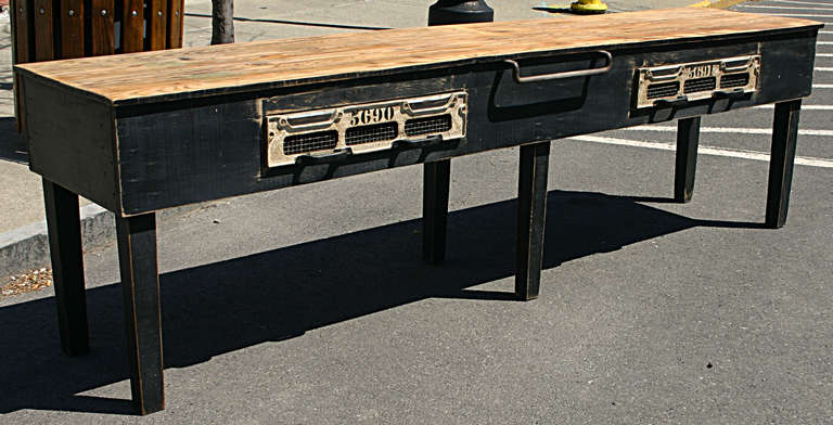 Great long console or work table. Black painted base with hemlock plank top. Interesting pair of vented drawers and cool iron bar over center leg. Six square tapered legs surrounded by deep apron.
