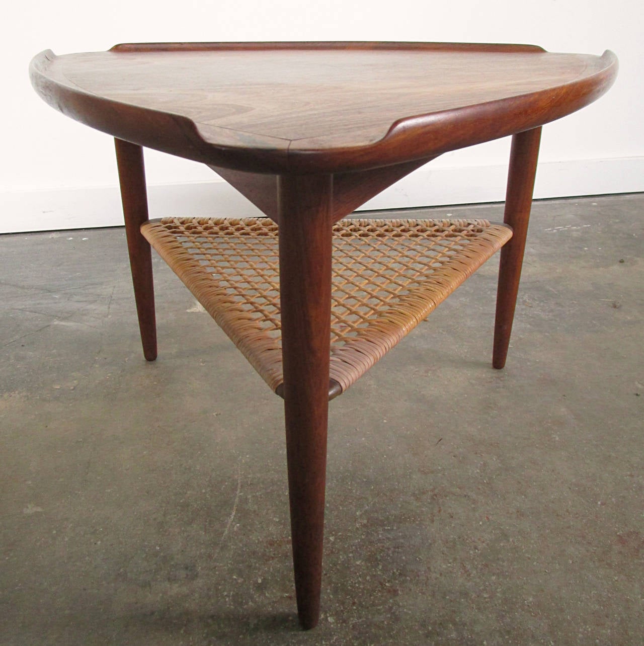 Guitar pick form, triangular table with medial cane shelf. Wonderfully grained rosewood top with raised edge detail. Danish export 1960s. warm patina, shows use.