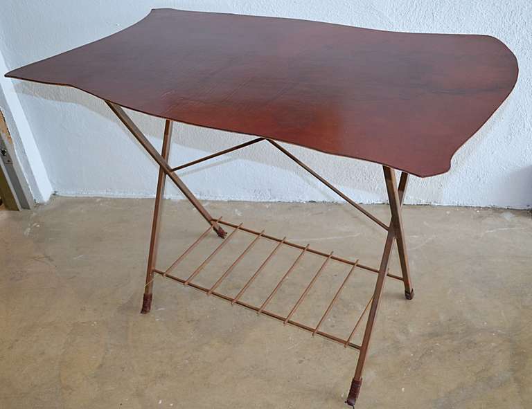 An early Jim Zivic design for Burning Relic. Oxblood leather on a biomorphic shaped wood top with shamfered edge rests atop square steel crossed legs with steel round bar shelf and leather wrapped feet. Labeled with burned in 