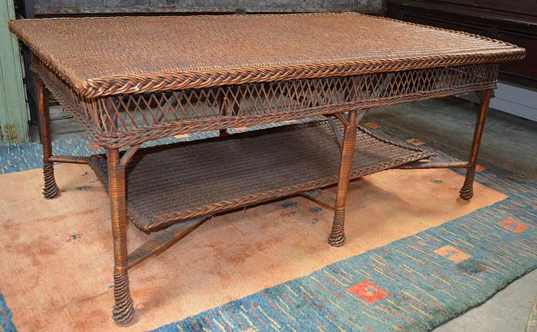 Rare reed and wicker six legged table with shelf circa 1930-1940. Tightly woven top with braided edge banding sits atop open weave apron with six wrapped legs and cross stretchers that support similar shelf. Great warm rich color. minor scuffs along