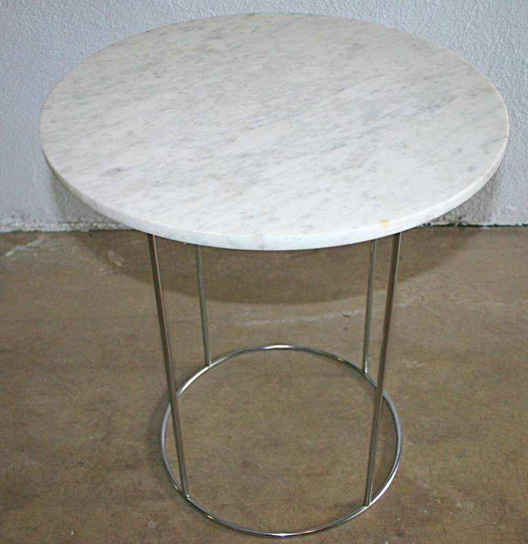 Delicate round marble side table on chrome base. White marble with subtle grey veining sits atop a round chrome ring with four chrome rod verticals.