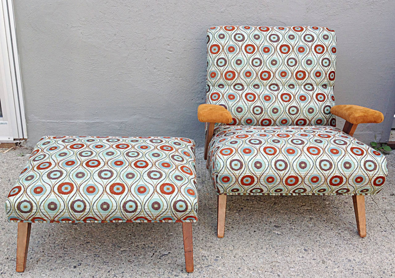 Stylish 1940s lounge chair and ottoman. Contoured back and seat in the scoop fashion. Square tapered legs. Floating arm rests in caramel suede. Ottoman is angled for optimum leg comfort. Newly reupholstered. Ottoman measure 26 x 19 x 13.75 H on the