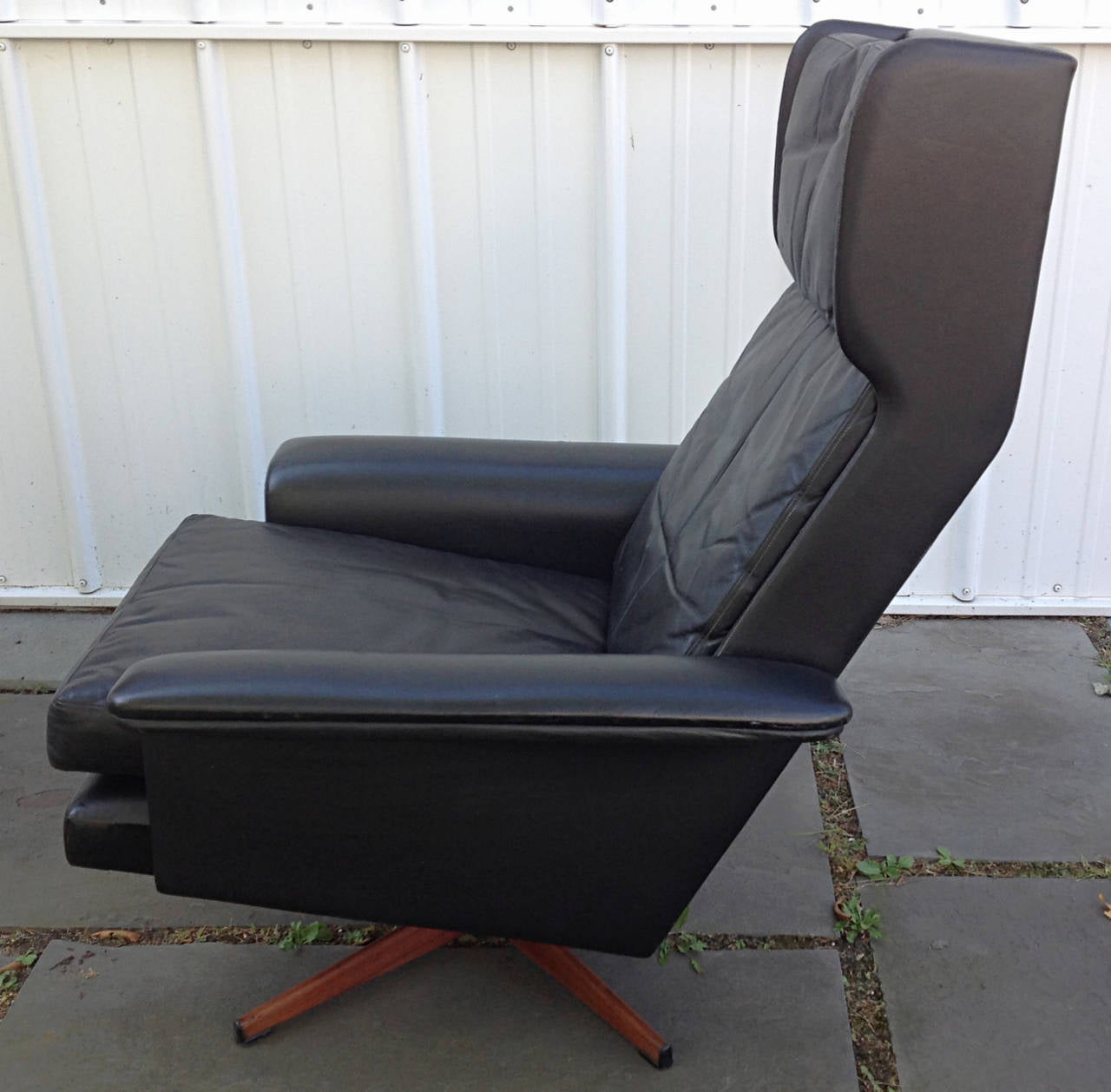 Danish wing back swivel lounge chair in black leather with faux rosewood four point metal base. Leather cushions are nicely broken in. Some abrasions to leather on outside edge of arms consistent with age and use.