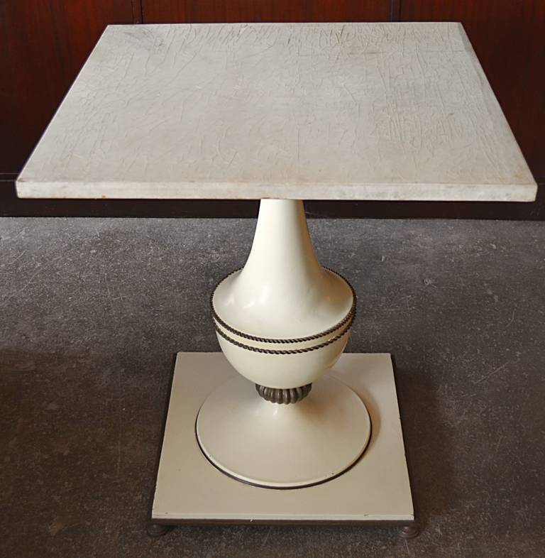 A nice pair of 1940s side tables. A square lacquered parchment covered top sits upon an enameled steel baluster form pedestal supported by a square base raised on round brass feet. nice brass rope details.