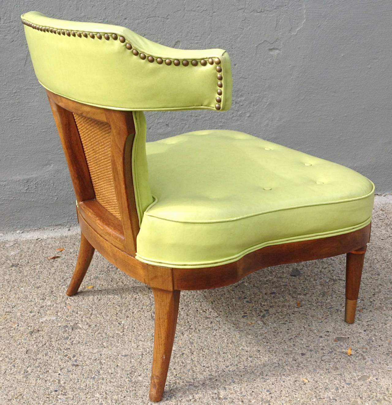 Wonderful low stylish slipper chair by Mastercraft, model 1099 from the Lombardy Collection circa 1954. Exposed walnut frame with cane inset back panel. Saddle shaped buttoned seat with yoke top rail over corseted back. Original chartreuse vinyl