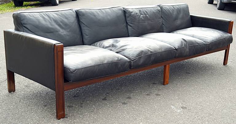 A long, low profile, clean lined Brazilian Rosewood and leather sofa. This is a solid rosewood constructed frame with four loose leather seat and back cushions and leather upholstered arms. Nice wear to the leather down filled cushions. The leather
