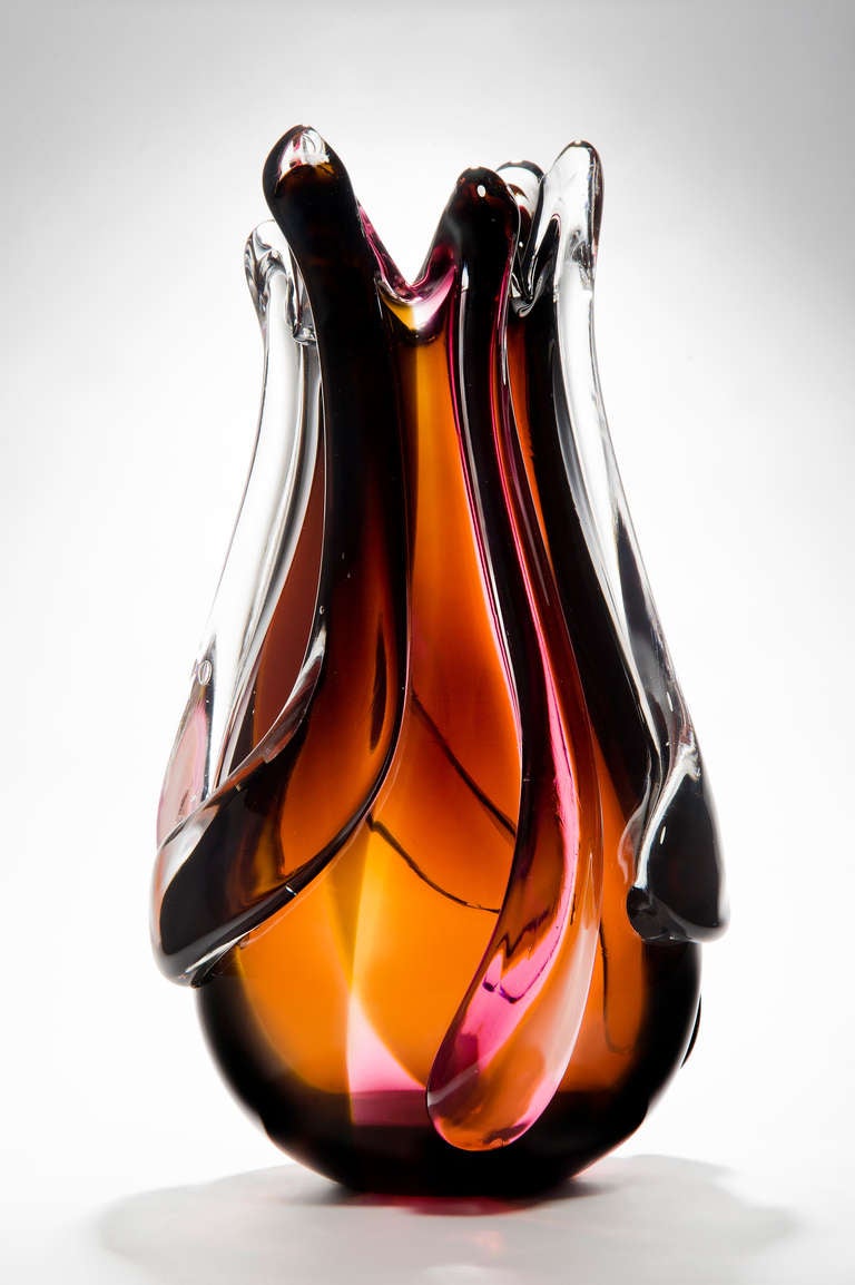 Le vase flamme est un grand et lourd vase sculptural en verre soufflé à la main, créé en utilisant des traînées de verre auburn, rose, orange et clair sur la surface. Soufflé par le maître souffleur britannique Simon Moore pour Nigel Coates. Un vase