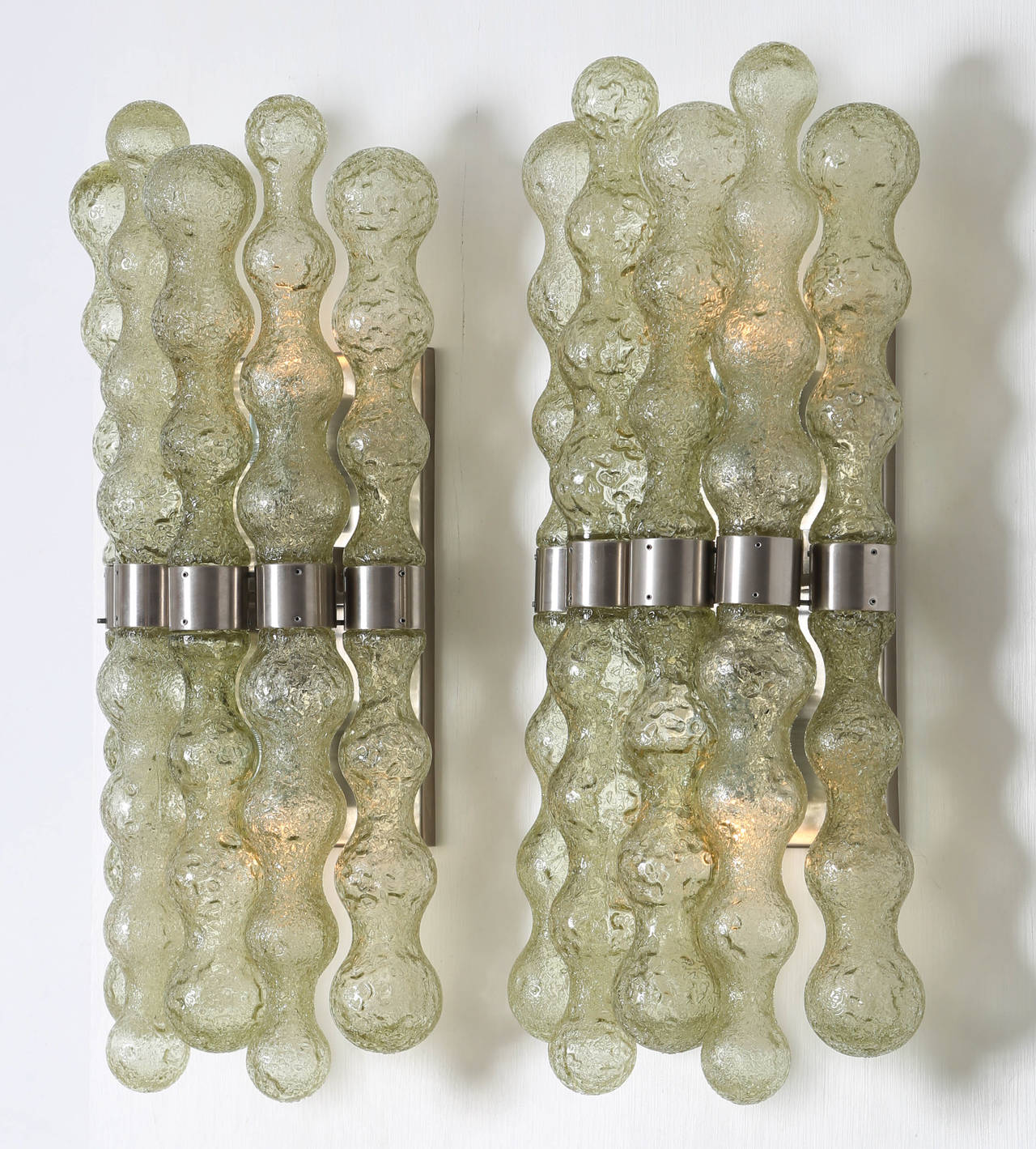 A pair of rare 1970s Murano glass sconces. Each sconce has ten transparent-green curvilinear pieces of textured glass held by stainless steel fittings. Each sconce holds two candelabra-base bulbs. These sconces are at the 1stdibs Gallery at the New