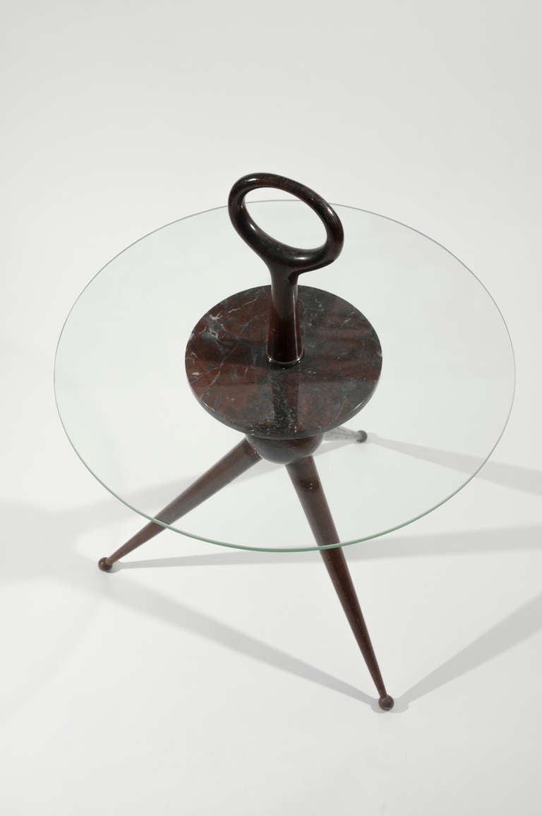 Elegant and portable table featuring a central ball with three tapered legs and a rounded handle. The circular glass top has a marble support shelf. Attributed to Pietro Chiesa, Fontana Arte. Stamped 