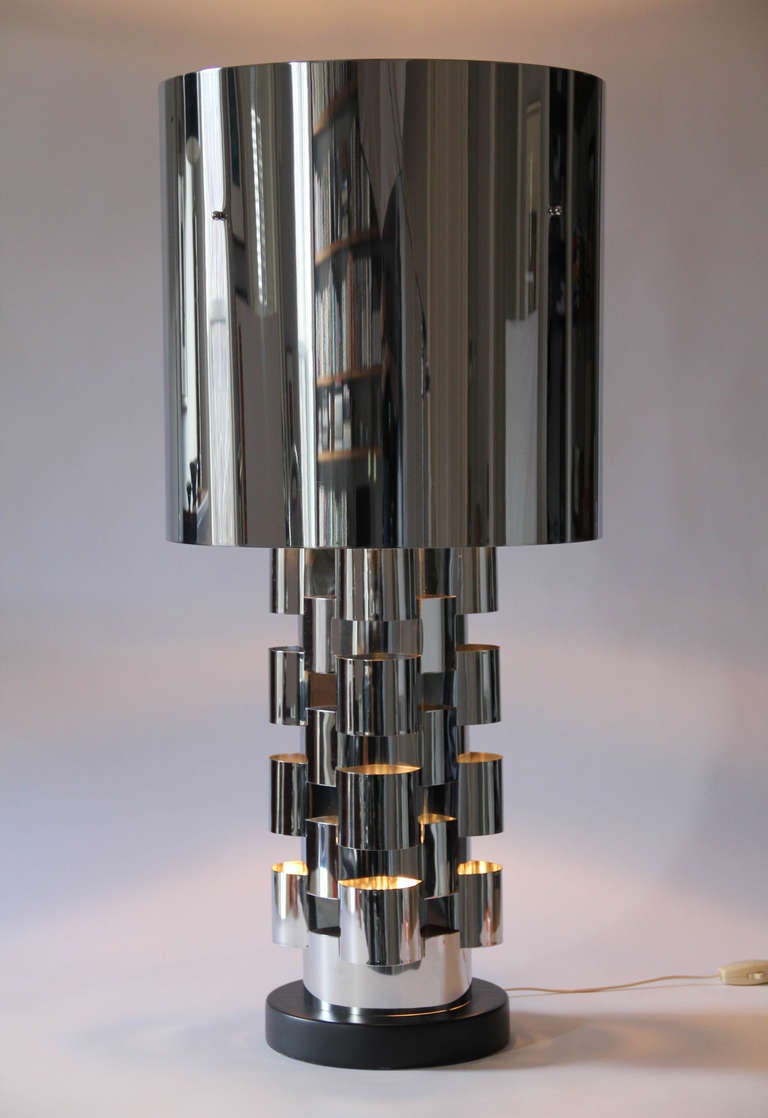 Wonderful large 1970s all-chrome table lamps by C. Jeré/Artisan House. Each lamp body, illuminated by a bulb within, is made of stacked interlocking shapes of bent chromed steel on a painted wood base. A second switch controls a three-way bulb under