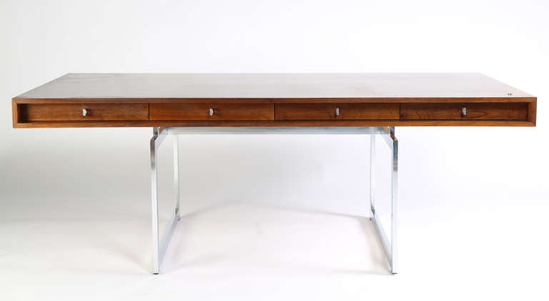 An elegant Danish design with a nod to International style, this impressively scaled desk floats on two rectangular chromed-steel supports. It is finished on all sides in beautiful rosewood in original condition and is striking from any angle. The