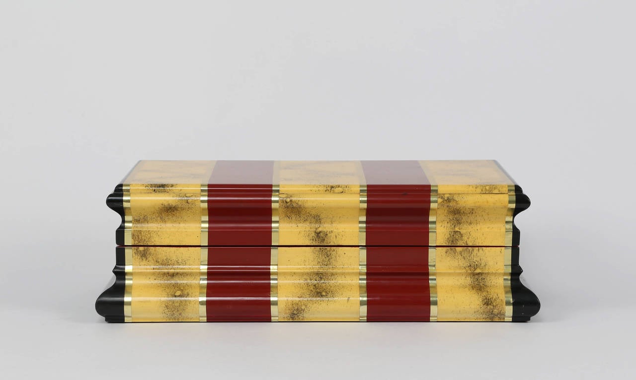 1980s hinged box with gray suede lining by Karl Springer. Exterior is painted in maroon and speckled-yellow bands with gold accent stripes and black-painted ends. 



