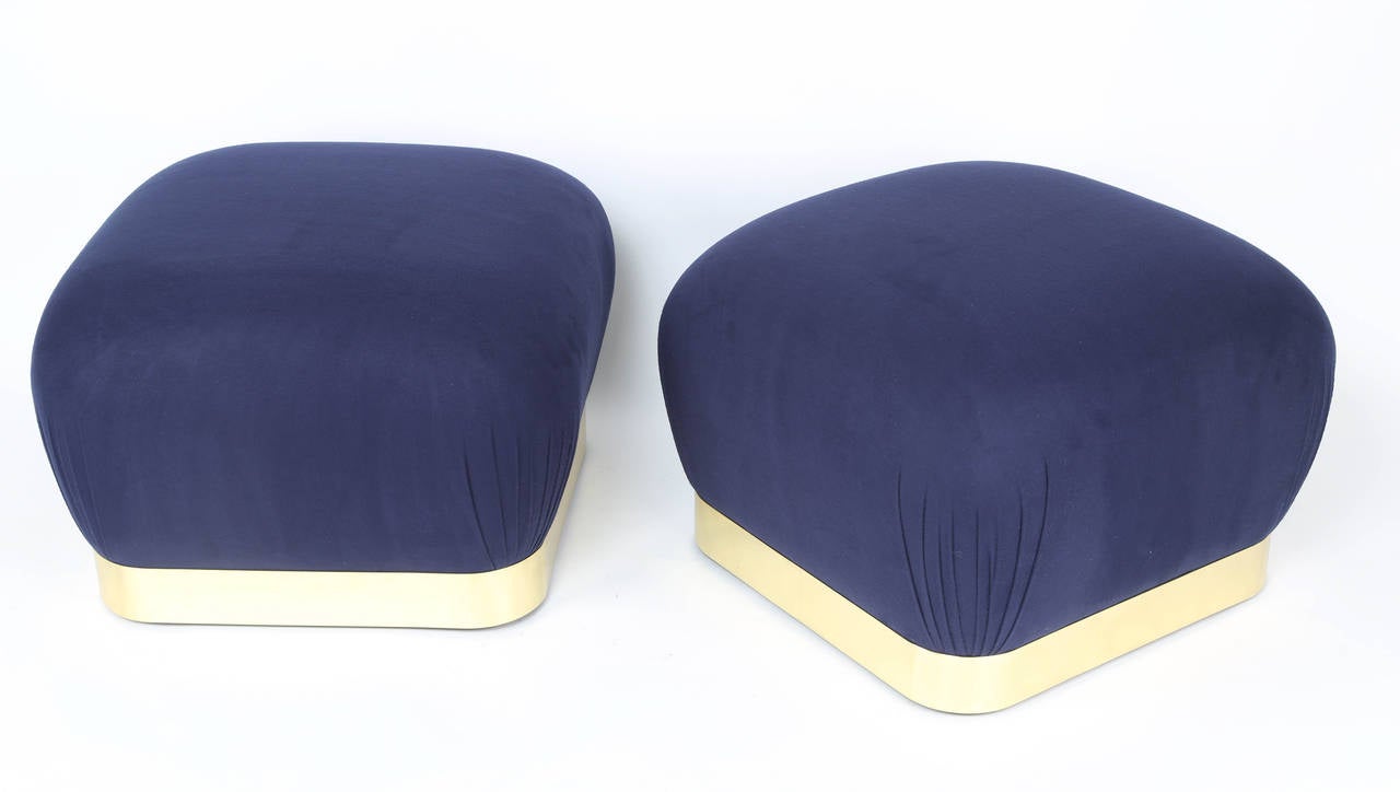 Pair of Karl Springer poufs on freshly polished and lacquered solid-brass bases; slightly raised on hidden casters. Signature Springer quality and understated style. Newly reupholstered in a soft, deep-blue wool fabric. Fabric swatch available.