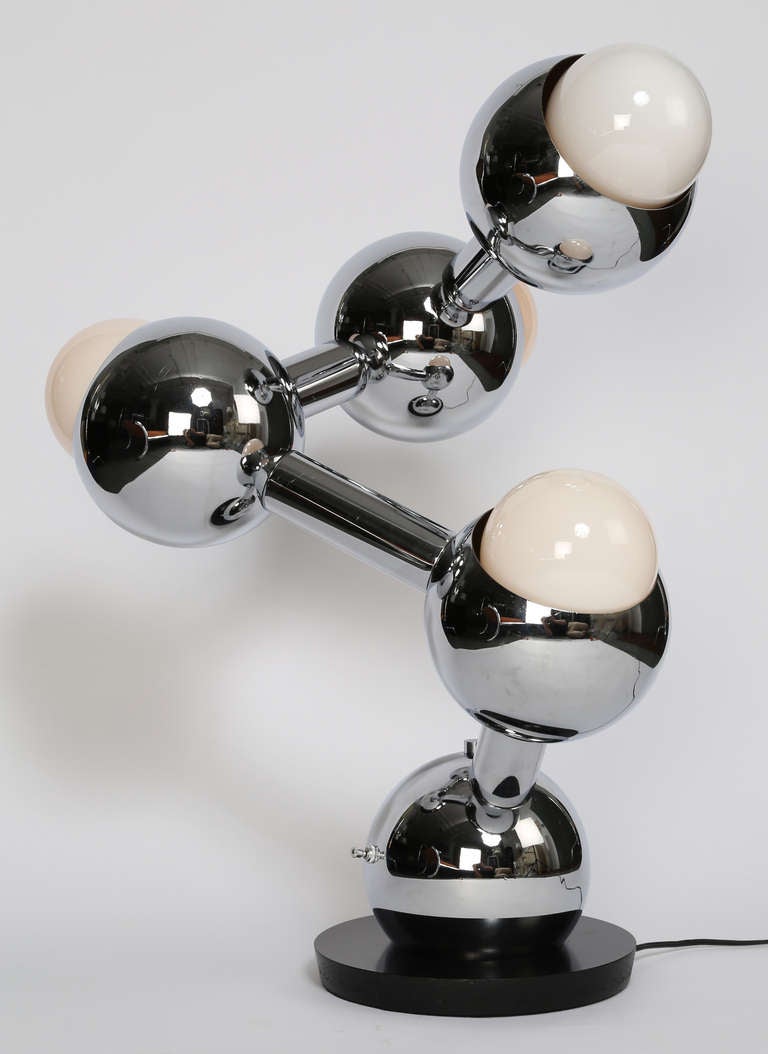 Each sphere of this extremely cool 1970s chrome table lamp, reminiscent of a molecular model, can be rotated, allowing an infinite number of configurations. A three-way switch on the base sphere illuminates the upper two bulbs alone, the lower two