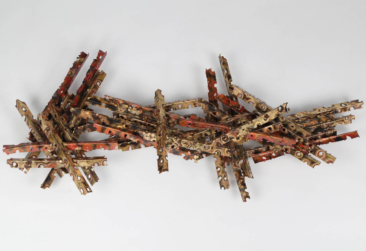 Dramatic wall sculpture by New York artist Silas Seandel, circa 1970s. Bent, torch-cut and pierced elements of patinated brass and copper intersect and stack at various angles. Signed with SS stamp to back of sculpture. 


