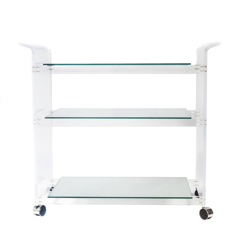 Fabulous three-shelf bar cart on casters. The Lucite slab side panels arch out at the top to form handles. Shelves are mirrored on underside for added bling. 



