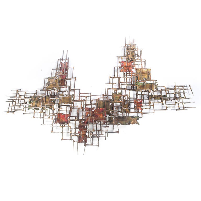 Enormous mixed-metals wall sculpture in an abstracted form, featuring interlocking nails with scattered flat torch-cut accent pieces in green and red hues. A statement piece rarely available in a size this large: 69” W x 46” H x 5” D. Etched