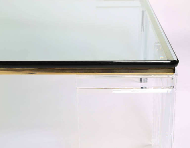 Glamorous and elegant 1970s lucite and glass coffee table with brass-plated square tubular steel accents, designed by Leon Frost of Lion in Frost Inc. Engraved signature on one leg.