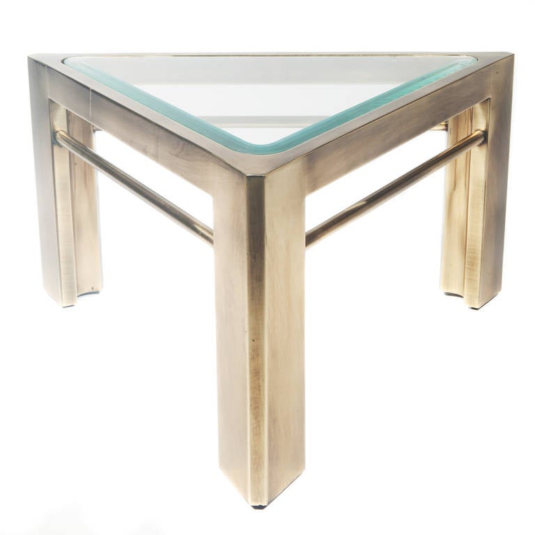 Triangular side or accent table in burnished brass with an inset beveled-glass top. 

