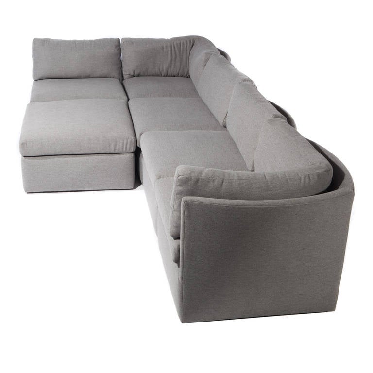 Flexible six-piece sectional sofa consisting of two corner pieces, three interior pieces and a single ottoman. Newly reupholstered in gray fabric. Each piece is 25-1/2" high to top of back, with cushions extending an additional 4". The