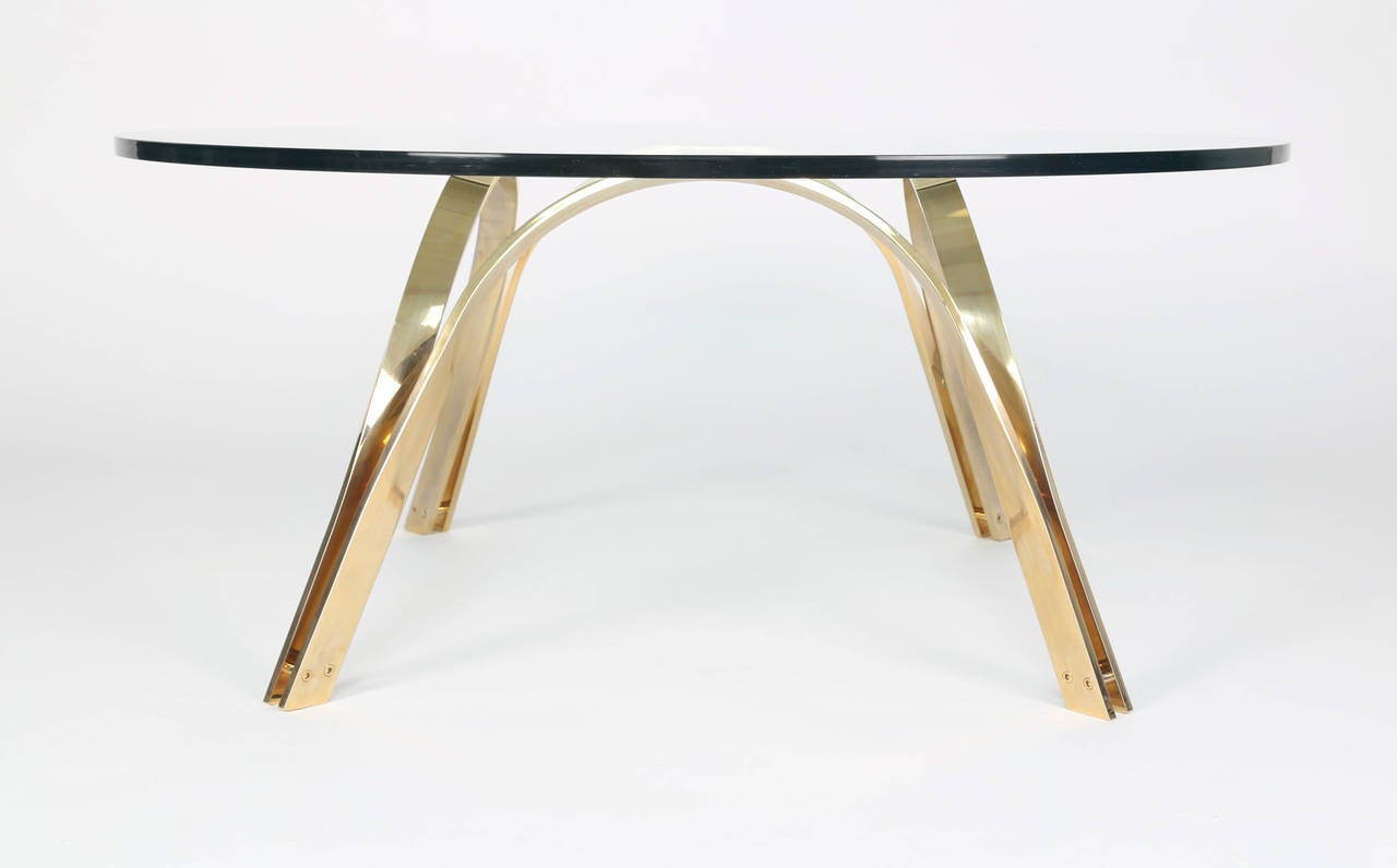 Sculptural brass-plated steel base supports a round 1/2-inch-thick glass top. 

