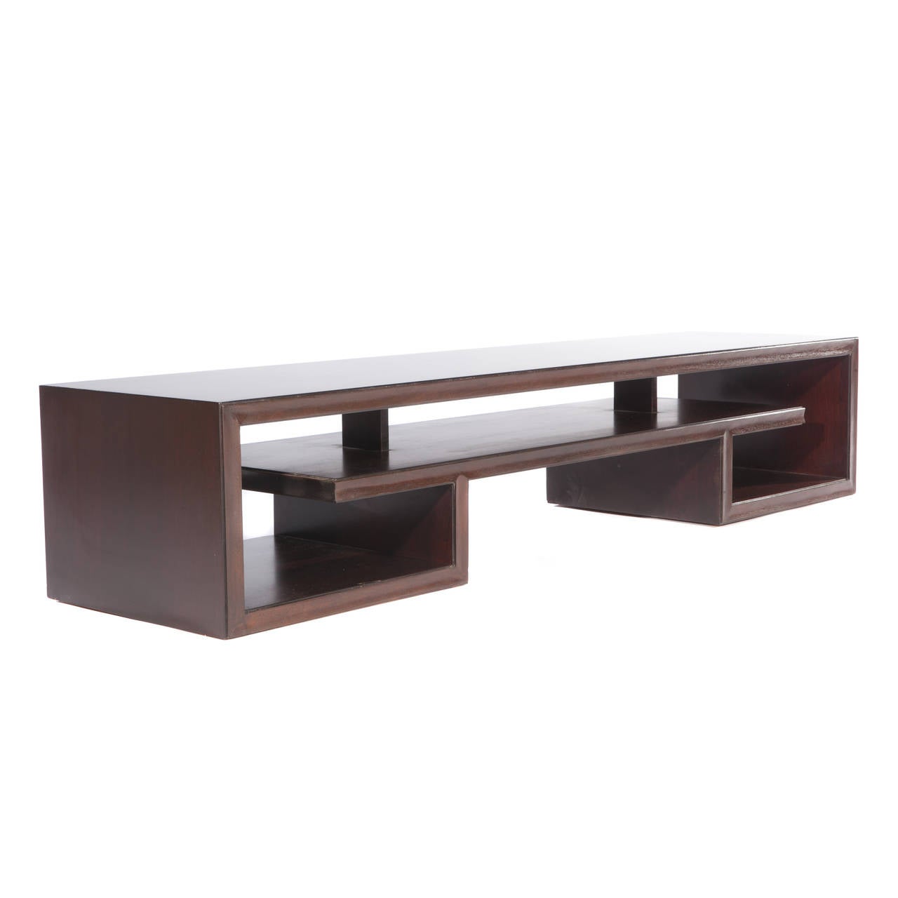 Long and low table featuring an architectural base with interlocking geometric shelf. Newly refinished in a dark, rich brown. We also have seen this piece used as a bench.