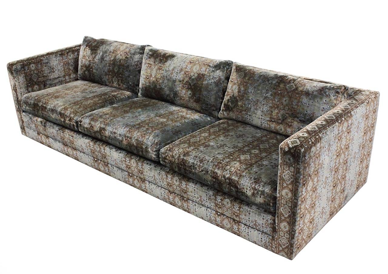 Sensational 1960s three-seat Dunbar tuxedo sofa in original patterned cut velvet in blue, brown and gold. The sofa is raised on a plinth base to give it a floating feel. Down-stuffed back cushions and down and foam seat cushions. Signed Dunbar on