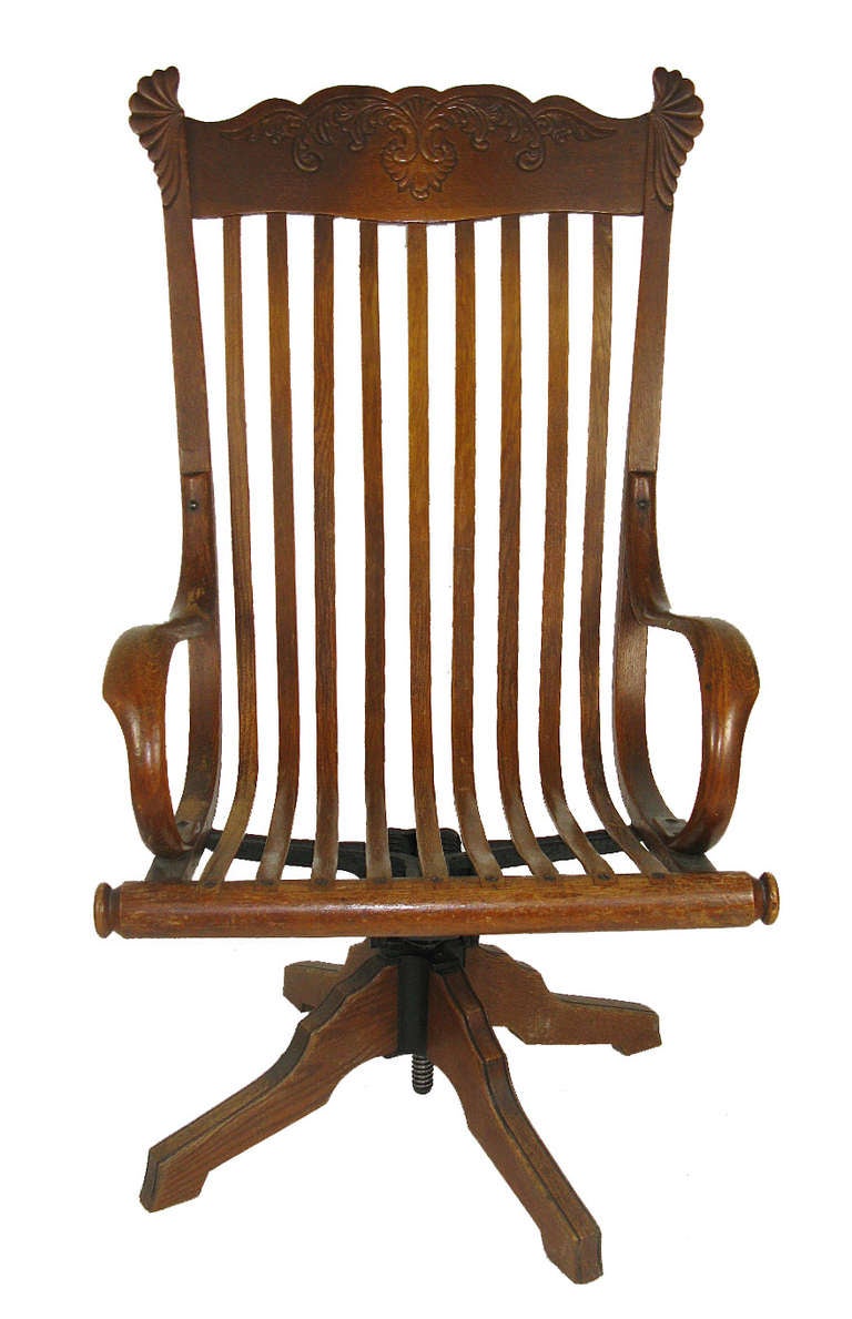 This chair is a rare design from the early 20th century, with single steam-bent oak slats forming the back and seat, a scalloped top edge, and a pedestal base. The metal mechanism allows it to swivel, adjust the seat height, and tilt back.