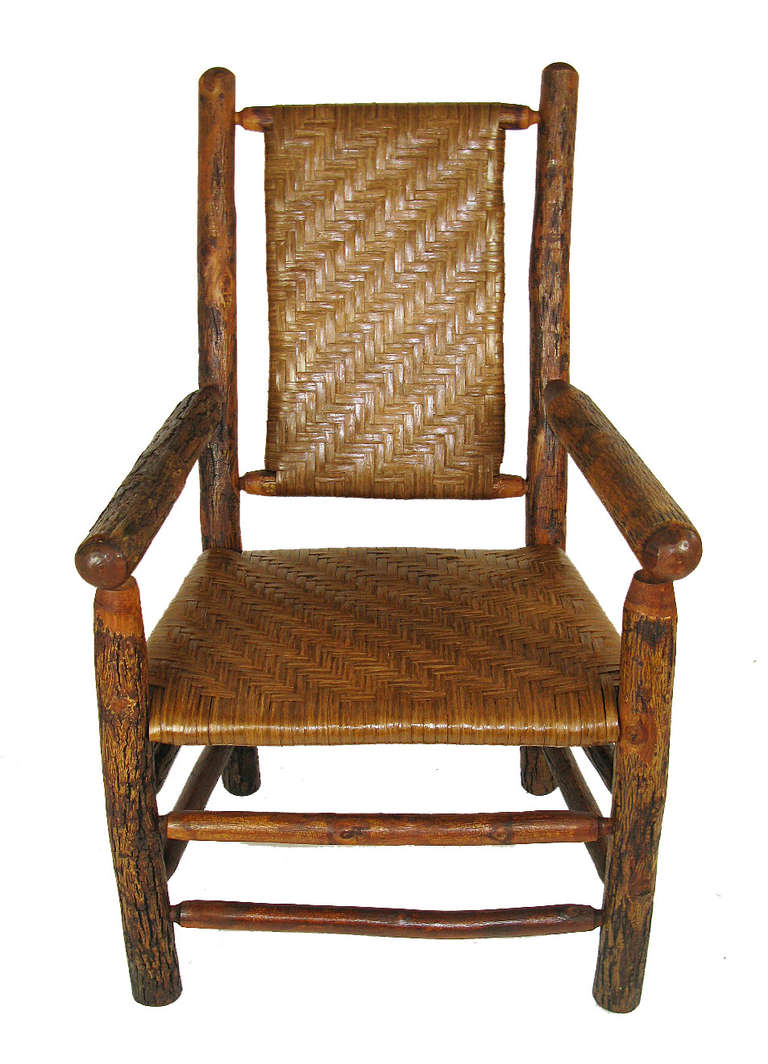 This large-scale, comfortable, and sturdy arm chair has a thick hickory pole frame with double stretchers along the front and sides of the base, and a seat and back that have been rewoven with flat fiber splint. This is a perfect sitting room or