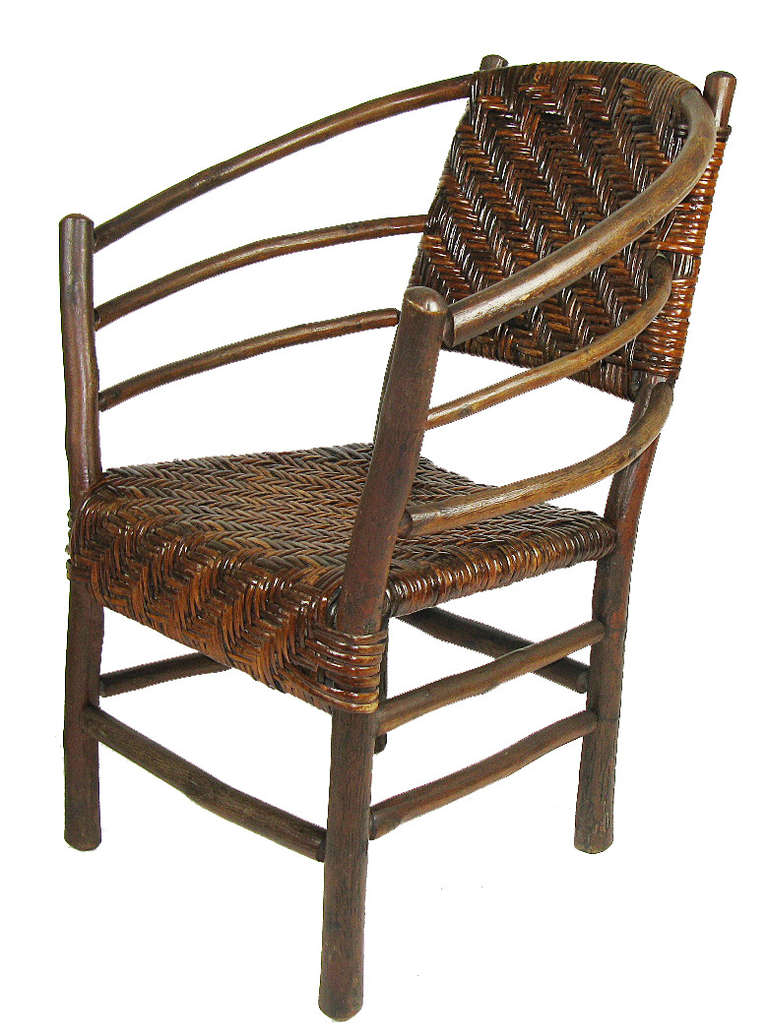 These classic hickory chairs, one arm chair and one rocking chair, have three-hoop arms and their original woven rattan cane seats and backs. The woven front aprons are an uncommon and handsome detail. Branded Indiana Hickory Furniture Company,