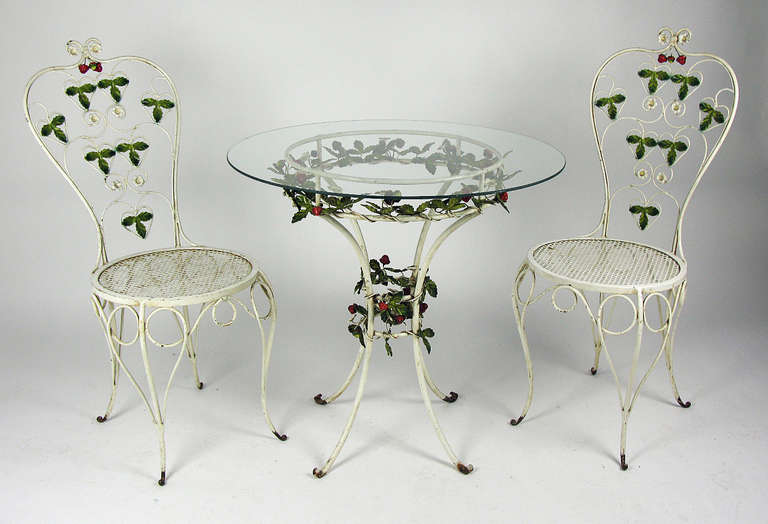 This charming furniture set features clusters of tole strawberries and leaves adorning the backs of two chairs and the base of a glass-topped 28