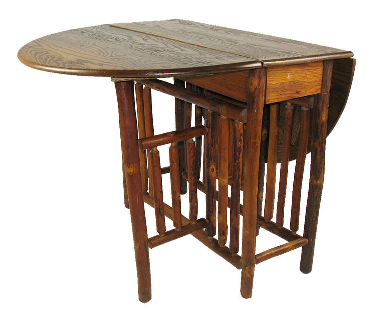This handsome, sturdy table has a multi-spindled hickory pole base and a drop-leaf oak top. Two chairs fit at the ends of the table when the leaves are open, or it functions as a sofa, console or center lamp table when one or both leaves are down.