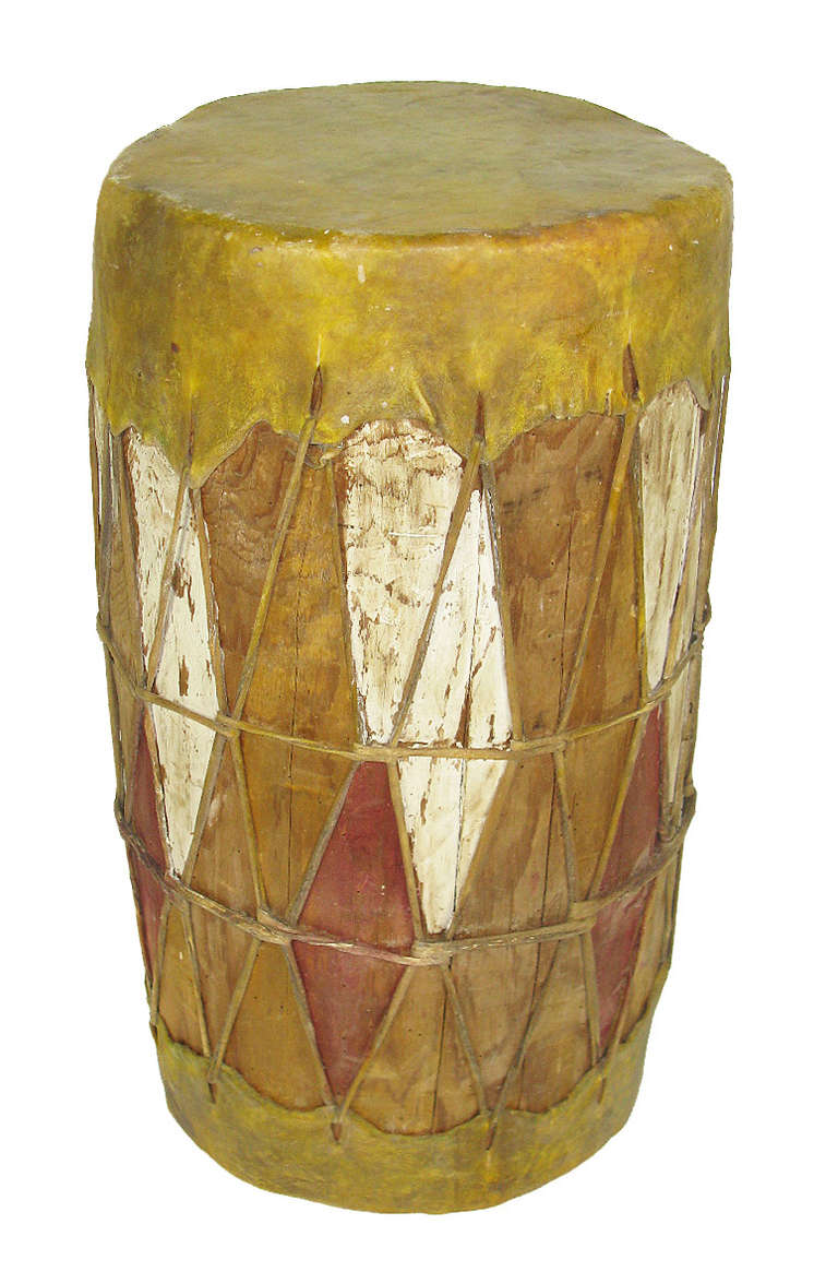 This traditional Native American drum from New Mexico is a hollow cottonwood log with a lashed hide top and bottom, and diamond-shaped red and white paint decoration. There is something inside the drum that produces a rattle when moved.Â We have