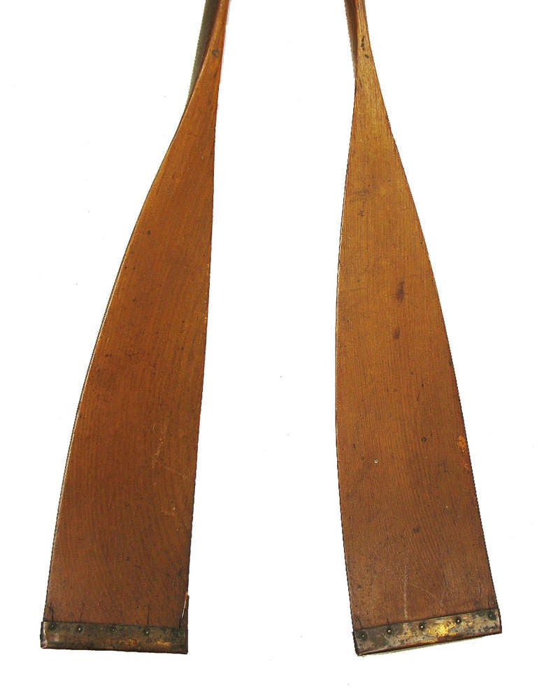 These are high quality, model-size wooden oars with leather grips, brass tacks and brass blade tips. It is rare to find good salesman's sample oars from this era, and these are a perfect size for decorative display.