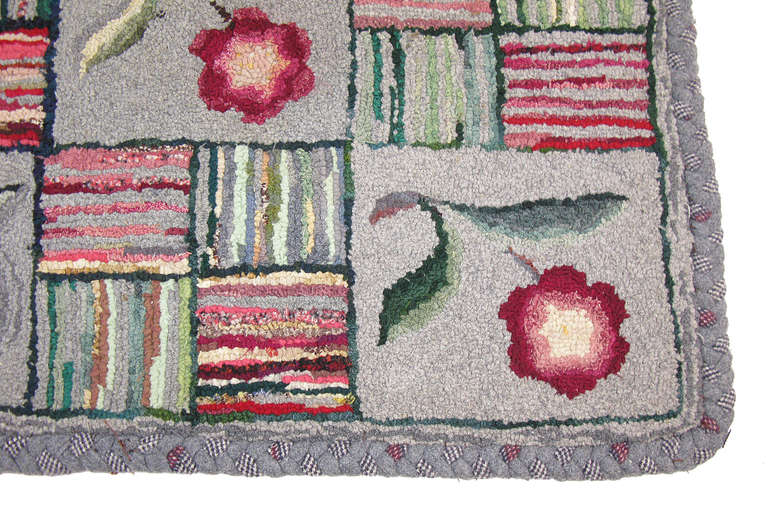A small, sampler-style hooked rug with alternating blocks of posies and striped squares, with an uncommon braided wool border. 

19