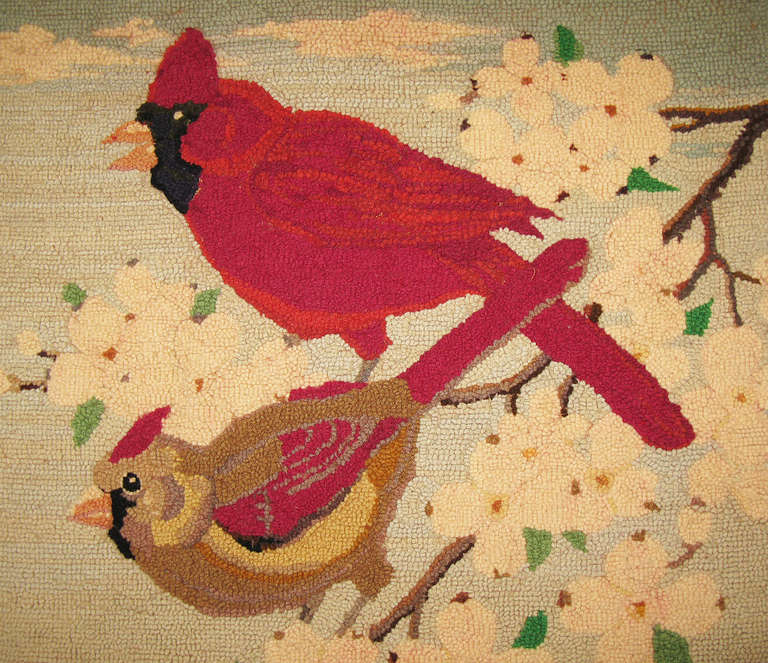 An appealing pictorial yarn-hooked rug depicting a male and female cardinal on a branch of flowering dogwood.