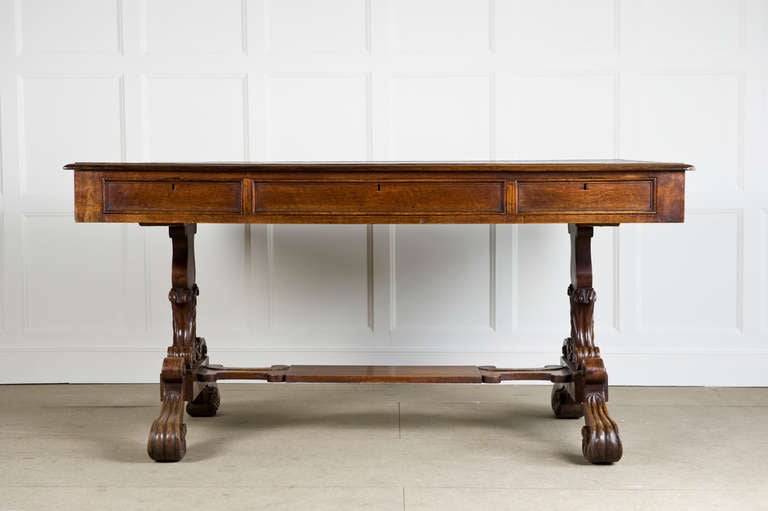 Oak standard end writing table circa 1840, with foliate carving to the ends and feet, having its original rexine top and the top having drawers on both sides