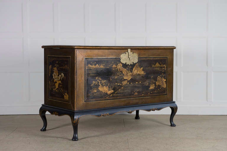 The moulded top, front, sides and back decorated with chinoiserie vistas all within a broad speckled gilt boarder, the sides with carrying handles, on a black-Japanned and parcel-gilt stand with shaped apron and cabriole legs
