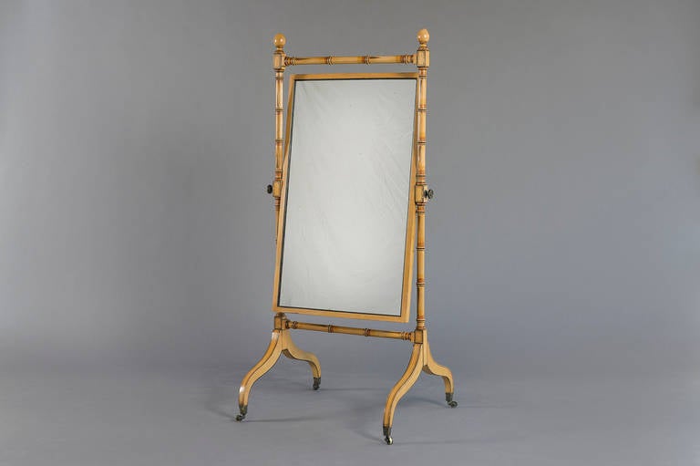 A regency framed cheval mirror with bevelled rectangular plate within a turned frame on sabre supports, with faux bamboo decoration, circa 1810